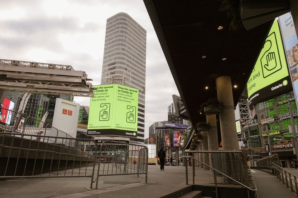 Painéis, aeroportos e transportes entram na nova fase da publicidade baseada em dados Painéis publicitários e banners vistos sob arranha-céus, junto a uma ponte e barreiras metálicas em uma área urbana.
