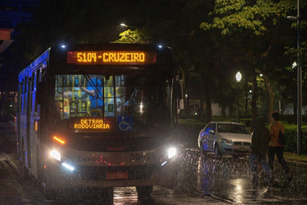 Tecnologia dá prioridade a ônibus e reduz tempo de viagem em corredor de BH Ônibus urbano circula à noite por uma via molhada de Belo Horizonte durante a chuva.