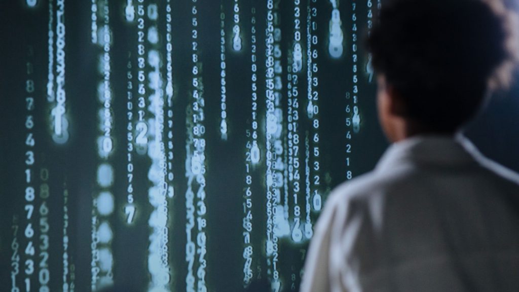 Usuário poderá descobrir como a inteligência artificial participou de um anúncio no Google Pessoa observa números luminosos exibidos em uma tela, em uma representação conceitual de tecnologia e dados.